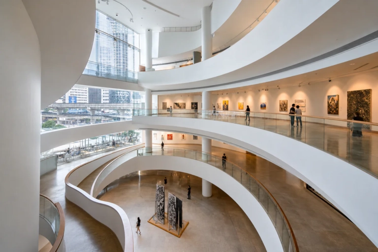 Modern interior of Bangkok Art and Culture Centre with curved gallery walkways and visitors in a bright cultural space near S
