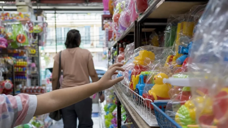 Main d’enfant vers des jouets colorés en magasin